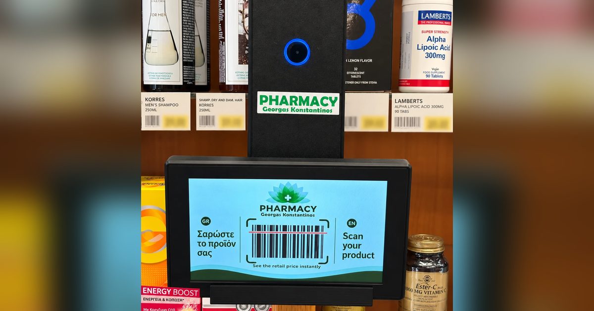 Η οθόνη του price checker στα ράφια του φαρμακείου με το μήνυμα «Σαρώστε το προϊόν σας / Scan your product» και ένα barcode.